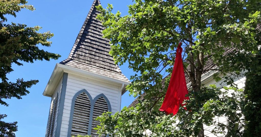 A red dress hanging from a tree outside St. Andrew, Courtenay. Photo by Marion Edmondson.